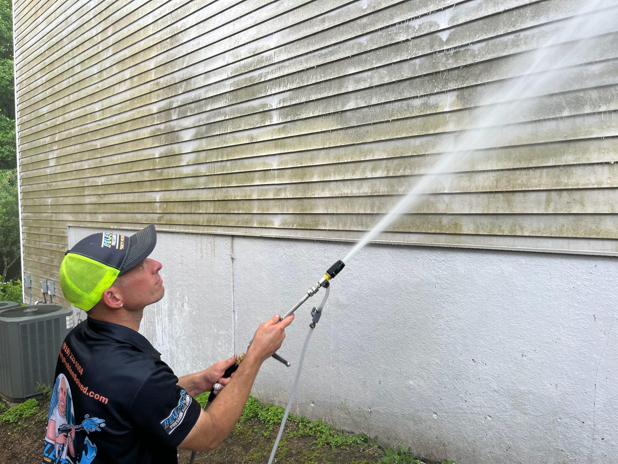 Griffin Roberts showing off his pressure washing expertise by removing mold and mildew from a residential building.